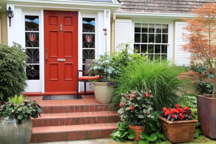 porch with red front door and lots of flowers